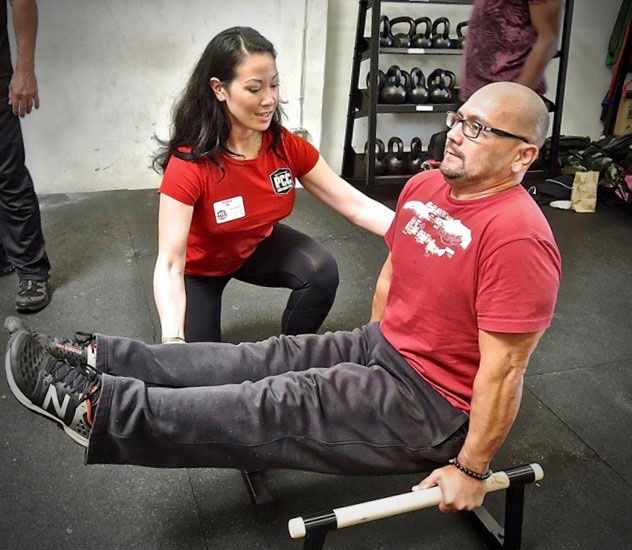 Annie Vo assists PCC Participant in L-Sit exercise